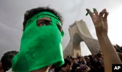 FILE - In this June 15, 2009, file photo, a demonstrator wears a green mask as hundreds of thousands of supporters of leading opposition presidential candidate Mir-Hossein Mousavi turn out to protest the result of the election in Azadi (Freedom) square.