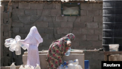 A Libyan woman displaced from the town of Tawergha fills containers with water at a displaced camp in Benghazi, Libya, on June 19, 2019. REUTERS/Esam Omran Al-Fetori