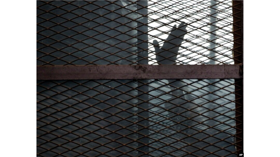 FILE - A defendant is seen caged in a courtroom in Torah prison, southern Cairo, Egypt, Aug. 22, 2015.