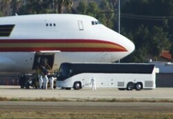 Personnel in biological hazard suits await passengers evacuated from Wuhan, the Chinese city at the heart of a growing outbreak of the deadly Novel Coronavirus shortly after the plane landed at March Air Reserve Base in Riverside, California.