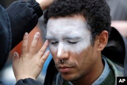 In this Oct. 31, 2018, file photo, a man, who declined to be identified, has his face painted to represent efforts to defeat facial recognition during a protest at Amazon headquarters over the company's facial recognition system, "Rekognition," in Seattle. (AP Photo/Elaine Thompson, File)