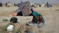 A displaced Afghan woman who fled her home due to fighting between the Taliban and Afghanistan. She burns small pieces of wood to make tea at the camp on the edge of the city of Mazar-e-Sharif, northern Afghanistan, Thursday, July 8, 2021. Thousands of people have fled the Taliban as they take northern Afghanistan. They fear their cruel rule. (AP Photo/Rahmat Gul)
