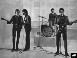 The Beatles are seen performing, date unknown. From left to right: Paul McCartney, George Harrison, Ringo Starr, and John Lennon.