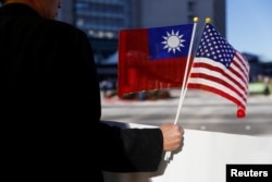 FILE - A demonstrator holds flags of Taiwan and the United States in support of Taiwanese President Tsai Ing-wen during an stopover after her visit to Latin America in Burlingame, Calif., Jan. 14, 2017.