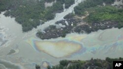 FILE -Oil is seen on the creek water's surface near an illegal oil refinery in Ogoniland, outside Port Harcourt, in Nigeria's Delta region, March 24, 2011.