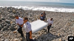 French police officers carry a piece of debris, the first trace of Malaysia Airlines Flight 370, in Saint-Andre, Reunion Island, July 29, 2015.