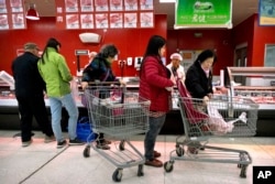 Customers shop for pork at a supermarket in Beijing, Friday, March 23, 2018.