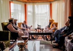In this handout photograph released by the Taliban, former Afghan President Hamid Karzai, center left, senior Haqqani group leader Anas Haqqani, center right, Abdullah Abdullah, second right, head of Afghanistan's National Reconciliation Council.