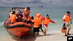 FILE - In this Sept. 14, 2014 photo, Chinese tourists disembark from an inflatable boat upon arrival in Quanfu island, part of the Paracels.