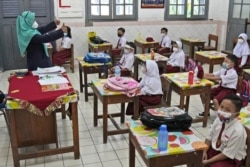 Students wearing face masks to help prevent the spread of COVID-19 attend a class during the first day of school reopening at an elementary school in Jakarta, Indonesia, Monday, Aug. 30, 2021(AP Photo/Dita Alangkara)