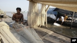 A Cambodian man fixes his fishing nets during the dry season on the Mekong river bank Tuesday, Feb. 28, 2012, in Phnom Penh, Cambodia. (AP Photo/Heng Sinith)