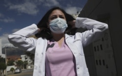 Dr. Maria Jose Casco adjusts her hair as she walks near her home in Quito, Ecuador, Wednesday, Aug. 5, 2020.