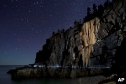Like a frozen waterfall, a wall of ice more than 40-feet-high stretches down to the high-tide line on Otter Cliffs overlooking the Atlantic Ocean, in this time-exposure made Thursday, March 6, 2014, at Acadia National Park in Maine.