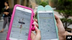 Women holding their smartphones show the ride-hailing apps Uber and Didi Chuxing at a residential compound in Beijing on Aug. 1, 2016.