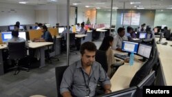 In this file photo, employees of ISGN work at their stations inside the company headquarters in the southern Indian city of Bangalore, India.