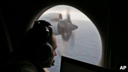 In this March 22, 2014 file photo, a flight officer aboard a Royal Australian Air Force plane searches for signs of missing Malaysia Airlines Flight MH370 in the southern Indian Ocean off Australia.