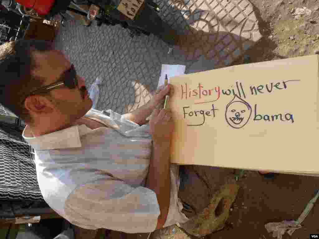 Một người biểu tình viết biểu ngữ "Lịch sử sẽ không quên Obama," 7 tháng 7, 2013 (S. Behn/VOA)