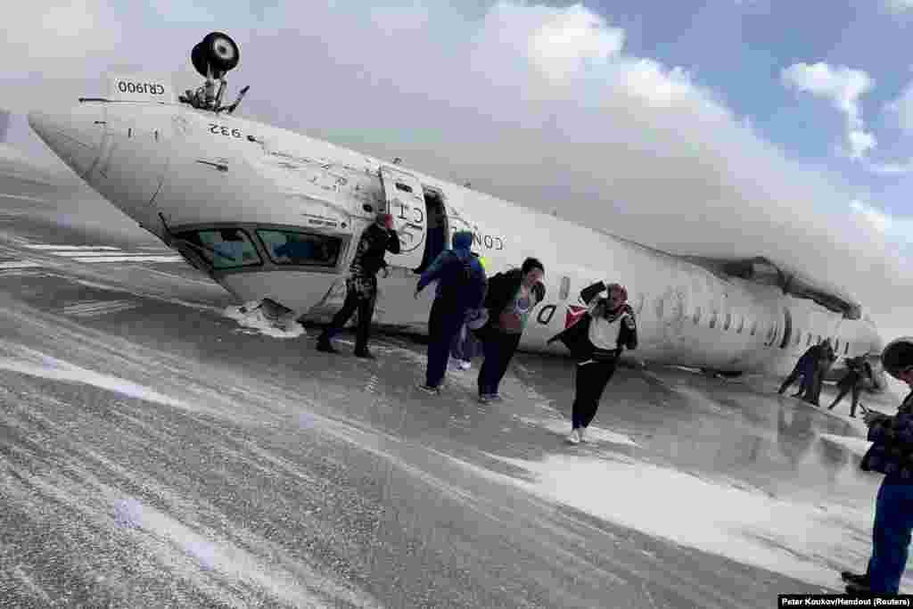 Passengers leave a Delta Air Lines CRJ-900 jet after it crashed on landing at Toronto Pearson International Airport in Mississauga, Ontario, Canada on February 17, 2025 in a still image from video.