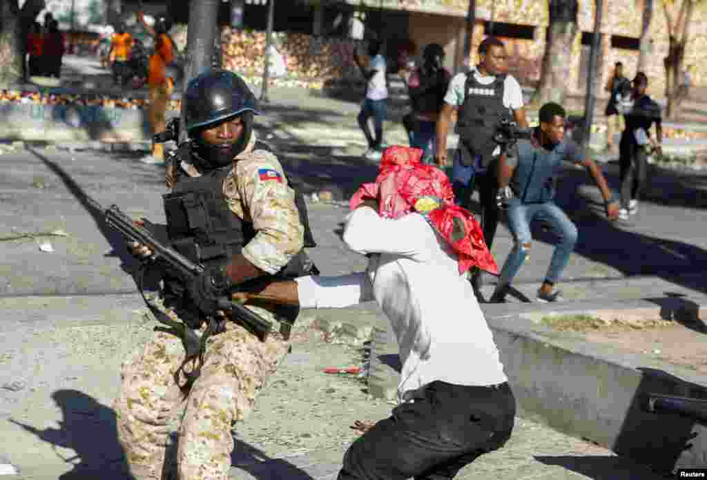 A demonstrator tries to grab the rifle of a police officer during protests against Haiti&#39;s President Jovenel Moise, in Port-au-Prince, Feb. 8, 2021.