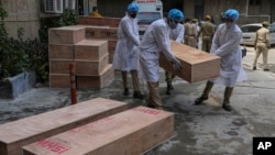 Jammu and Kashmir State Disaster Response Force soldiers carry empty coffins for transporting bodies of people who died of COVID-19 outside government medical hospital in Jammu, India, Wednesday, May 19, 2021. (AP Photo/Channi Anand)