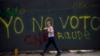 Una transeúnte pasa frente a un grafitti en Caracas que censura la elección presidencial del 20 de mayo, califcándola de fraude.