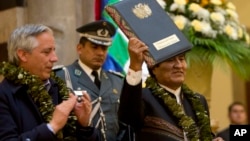 Bolivia's President Evo Morales holds up the folder containing the newly-signed coca law at the presidential palace in La Paz, Bolivia, Wednesday, March 8, 2017. (AP Photo/Juan Karita)