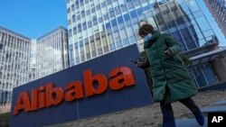 A woman wearing a face mask runs past the offices of Chinese e-commerce firm Alibaba in Beijing on Dec. 13, 2021. (AP Photo/Andy Wong)