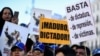 La gente sostiene pancartas que dicen "Maduro, dictador!" y "Basta de dictadura, represión y víctimas" durante una manifestación convocada por ciudadanos venezolanos contra el presidente Nicolás Maduro, en Madrid.