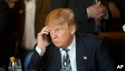 Republican presidential candidate Donald Trump listens to his mobile phone during a lunch stop in North Charleston, S.C., Feb. 18, 2016. Trump tweeted that he now uses government phones. 