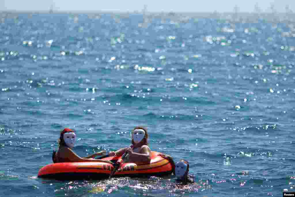 People take part in a performance which simulates the sinking of a dinghy with immigrants as they sail from Europe to Africa, during a protest in favor of the free movement of persons at the borders, at the Mediterranean Sea on La Malagueta beach in Malaga, Southern Spain.