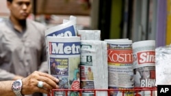 A man takes a copy of newspaper at a grocery shop in Shah Alam, Malaysia, Monday, March 26, 2018. Malaysia's government on Monday proposed new legislation to outlaw fake news with a 10-year jail term for offenders. (AP Photo/Sadiq Asyraf) 
