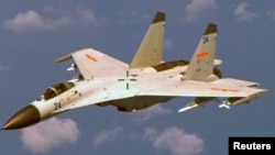 A Chinese J-11 fighter jet is seen flying near a U.S. Navy P-8 Poseidon about 215 km (135 miles) east of China's Hainan Island in this U.S. Department of Defense handout photo taken August 19, 2014. China on Saturday called US criticism of an approach by one of its jets to a US Navy patrol plane off the Chinese coast earlier this week "completely groundless" and said its pilot had maintained a safe distance from the US aircraft. Picture taken August 19, 2014. REUTERS/U.S. Navy/Handout 