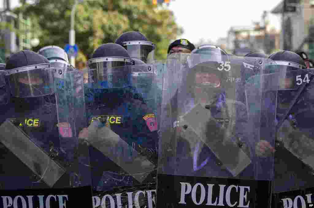 Police in riot gear stand guard as they face pro-democracy protesters during a rally in Bangkok, Thailand.