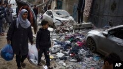 Palestinos caminan junto a escombros dejados por un ataque aéreo israelí durante la madrugada en Rafah, en el sur de la Franja de Gaza, el 9 de febrero de 2024.