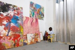 Ace-Liam Nana Sam Ankrah, who will turn two in July, paints amidst his own art work at his mother's art gallery in Accra, Ghana, Monday, May 27, 2024. (AP Photo/Misper Apawu)