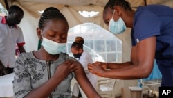 A nurse administers an AstraZeneca vaccination against COVID-19, at a district health center giving first, second, and booster doses to eligible people, in the low-income Kibera neighborhood of Nairobi, Kenya, Jan. 20, 2022. (AP Photo/Brian Inganga)