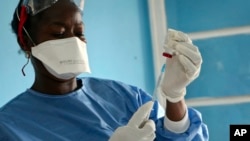 FILE - In this Wednesday, May 30, 2018 file photo, a healthcare worker from the World Health Organization prepares Ebola vaccines to give to frontline aid workers, in Mbandaka, Congo. 