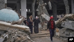 ARCHIVO - Un grupo de palestinos camina cerca de las ruinas de una mezquita afectada por ataques aéreos en la ciudad de Gaza, el 7 de marzo de 2025. Un grupo de expertos busca documentar denuncias de crímenes de lesa humanidad en la región. 
