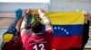 Migrantes venezolanos cuelgan una bandera nacional venezolana durante una "consulta popular" convocada por la oposición venezolana. Bogotá, Colombia. Diciembre 12, 2020.