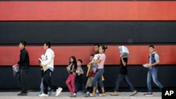 Immigrant families walk along a sidewalk on their way to a respite center after they were processed and released by U.S. Customs and Border Protection, Sunday, June 24, 2018, in McAllen, Texas. (AP Photo/David J. Phillip)