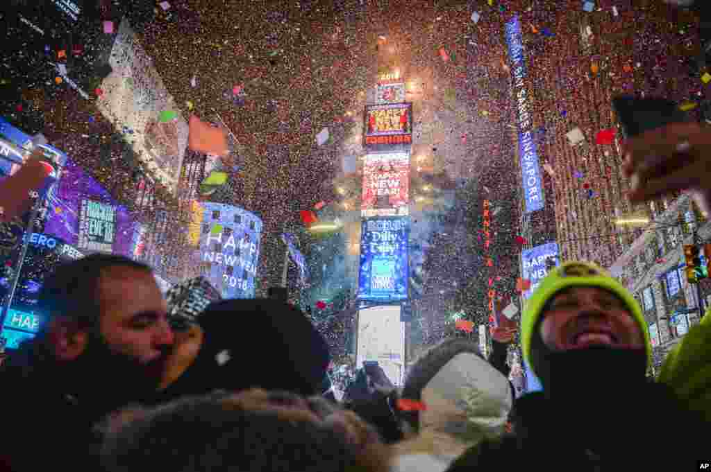 People celebrate as confetti falls down after the countdown to midnight in Times Square, Jan. 1, 2018, in New York.