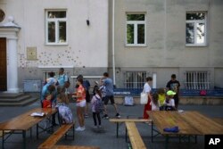 Ukrainian refugee children gather outside the Lauder Morasha Jewish school in Warsaw, Poland, Thursday, July 28, 2022. A special summer camp run by Jewish organizations has brought Jewish volunteers from the former Soviet Union to Warsaw to help Ukrainian children. (AP Photo/Michal Dyjuk)