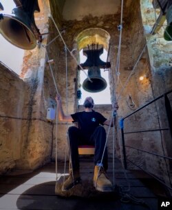 Joan Carles Osuna, a student of the Vall d'en Bas School of Bell Ringers, plays the bells at the 12th-century Sant Romà church, at the village of Joanetes, about two hours north of Barcelona, Spain, Saturday, June 29, 2024. (AP Photo/Emilio Morenatti)
