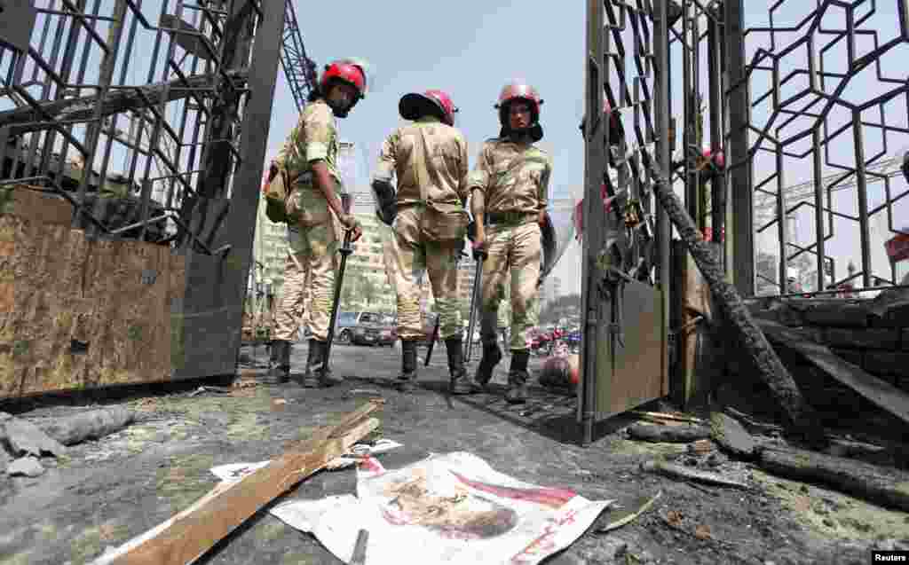 2013 年8月15日,开罗纳赛尔城,被废黜的埃及总统穆尔西的海报被扔在地上,军警站在被焚烧的清真寺外面