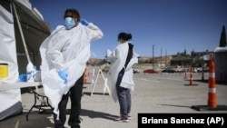 In this Oct. 26, 2020, file photo, Jacob Newberry puts on new PPE at the COVID-19 state drive-thru testing location at UTEP in El Paso, Texas. (Briana Sanchez/The El Paso Times via AP)