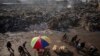 Palestinos pasan junto a montones de basura ardiendo en la Ciudad de Gaza, que no cuenta con sistema de recogida de basuras, el 12 de febrero de 2025.