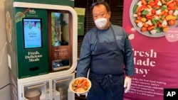 Kang Kuan, vice president of culinary at Chowbotics, holds a custom salad made by his company’s robotic salad-making kiosk at the company’s headquarters in Hayward, Calif., on Tuesday, June 23, 2020. (AP Photo/Terry Chea)