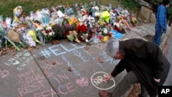 A man adds his comments to a spontaneous memorial of flowers and sidewalk writing that has appeared a block from the Tree of Life Synagogue on Monday, Oct. 29, 2018. (AP Photo/Gene J. Puskar)
