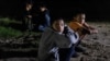 Migrantes menores no acompañados de Honduras a la orilla del río mientras esperan ser escoltados por la Patrulla Fronteriza después de cruzar el río Grande hacia Estados Unidos desde México, 9 de julio de 2021.