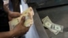 Un hombre cuenta sus bolívares y dólares para pagar artículos en un mercado en Caracas, Venezuela, el domingo 19 de mayo de 2019.
